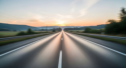 Naklejka premium A long, straight road stretches into the distance, leading towards a beautiful sunset.