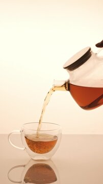 Teapot with black tea pouring in cap. 4K Video