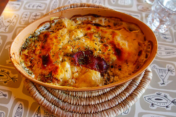 Potato gratin with duck meat, cheese and rosemary on a table. Traditional french dish