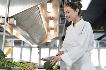 Cooking, Kitchen. Female chef wearing white apron cooking in kitchen at restaurant