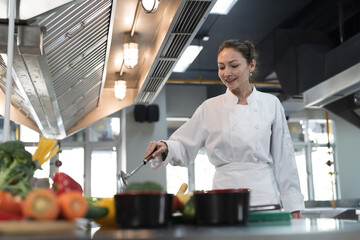 Cooking, Kitchen. Female chef wearing white apron cooking in kitchen at restaurant