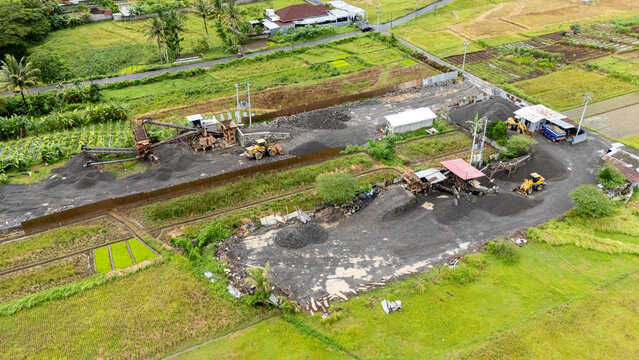 Heavy machinery operates at a toll road construction site in lush Central Java fields