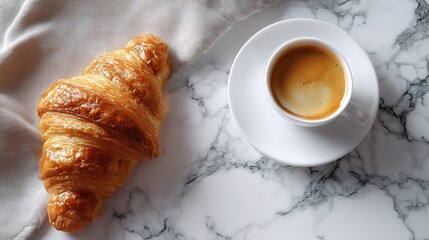 Freshly baked golden croissant next to a steaming cup of espresso coffee on a white saucer set against a marbled surface with a soft fabric drape