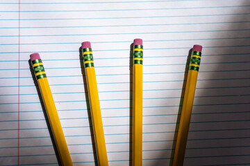 close-up of pencils against lined notebook paper in moody lighting 