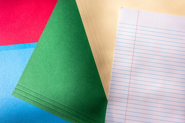 flat lay of colorful business folders and lined notebook paper in moody lighting 