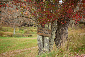 Private property signs, lichen trees, red fall leaves, rural boundary
