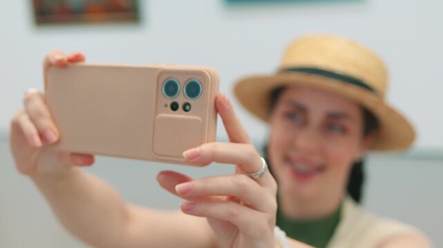 Museum aesthetics through the eyes of a young female visitor taking selphie photos of modern paintings. Cultural experience and digital interaction.