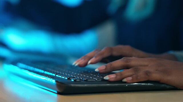A close-up of a woman's hands typing on a keyboard with blue ambient light. Digital work, coding, data entry, or customer service. Concepts of technology, cybersecurity, and night shifts in office