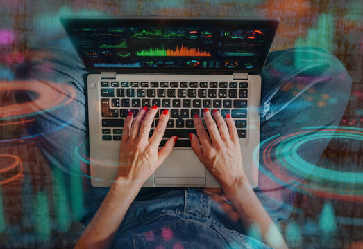 Hands typing on laptop with futuristic data interface overlays