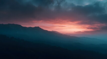 Obraz premium Dramatic mountainous landscape at dusk with vibrant orange and pink hues painting the sky
