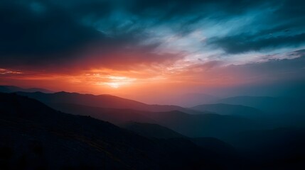 Obraz premium A stunning panoramic vista of layered mountain ranges at dusk illuminated by a dramatic sky awash in vibrant orange and blue light