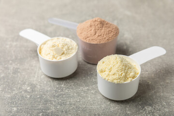 Protein powder. A spoonful of protein powder on a table. Different flavors of whey protein powder. Sports nutrition concept. Gym. Amino acid food supplement, creatine powder. Copy space.