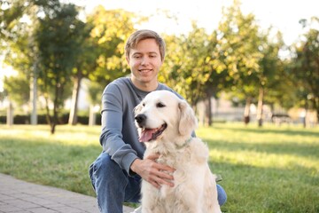 Man with his adorable golden retriever dog in park. Space for text