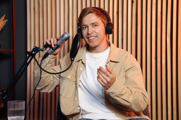 Podcast host in headphones recording talk show indoors, view from camera