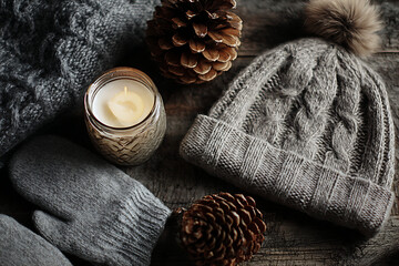 Cozy winter essentials a knitted beanie, mittens, candle, and pinecones evoke warmth and hygge comfort perfect for seasonal promotions