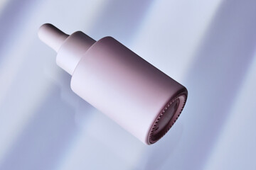 Bottles of facial serum in background with wide blue stripes.