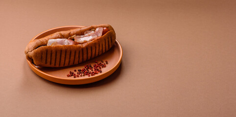 A hot dog with sausage, bacon, sauces, and a bun, unhealthy takeaway food. A hot dog with bacon