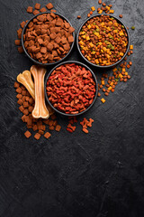 Assortment of dry food for pets. On a black stone background. Free space for text.