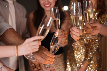 Friends celebrating New Year with sparklers and wine glasses indoors, closeup