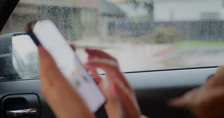 Close-up of person using a smartphone inside a car, tapping and scrolling on the touchscreen with a rainy window in the background. Modern technology, communication, mobility, and digital lifestyle. - Powered by Adobe