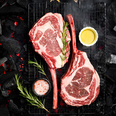 Two raw juicy Tomahawk steaks are cooked over hot coals. Barbecue. Top view.