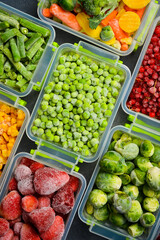Various vegetables and berries frozen in plastic containers. Top view. Frozen food. Vertical photo.