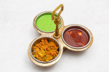 Condiments indiens – sauce verte (chutney à la menthe), sauce piquante (pickles/achards) et sauce sucrée (chutney au tamarin), photographie culinaire. Sauces indiennes.