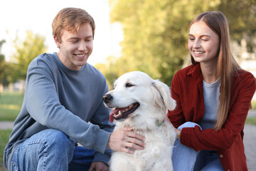 Happy couple with their adorable golden retriever dog in park