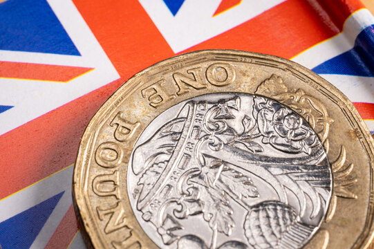 United Kingdom pound coin resting on a British flag, symbolizing the nation's economic challenges, debt, and the financial mild stagflation scenario - Powered by Adobe