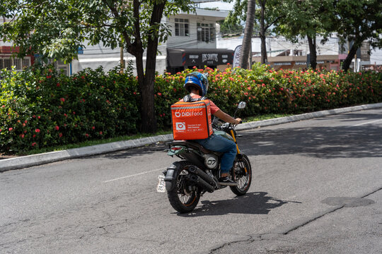 Didi driver food delivery service riding his motorbike with orange box. Sharing collaborative economy concept in South America. Guadalajar, Jalisco, Mexico, Otc. 2, 2025.