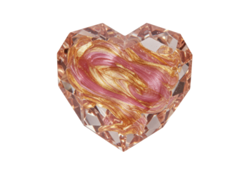 Isolated heart-shaped crystal paperweight with glittery gold and pink paint filling swirls