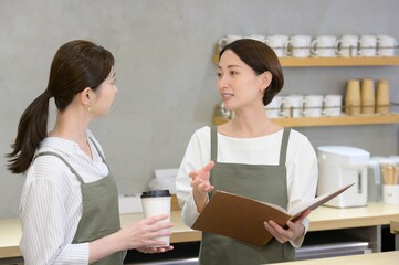 カフェの受付でメニューを見て話し合う日本人女性