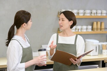 カフェの受付でメニューを見て話し合う日本人女性