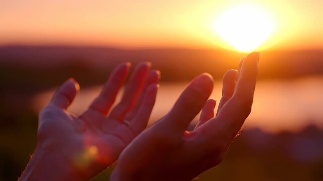 Hands raised in prayer towards the golden sunset. A spiritual gesture of hope, faith, and gratitude. Connecting with nature concept