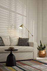 Beautiful living room with lamp, stylish furniture and plant. Interior design