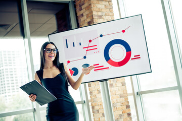 Confident businesswoman presenting data insights with a smile in a modern office setting during a professional meeting