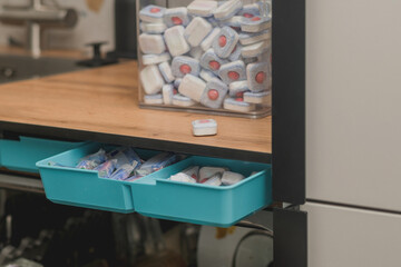 Kitchen with a dishwasher and a container filled with dishwasher tablets.