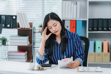 Overwhelmed: The burden of work weighs heavily on a young office worker. She sits at her desk,...