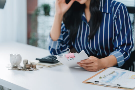 Focused Financial Analysis: A businesswoman diligently reviews financial documents and a calculator at her office desk, meticulously managing money and resources.
