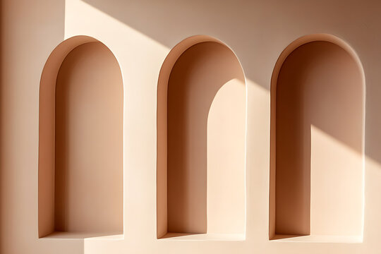 Three arched alcoves in a pale peach wall are illuminated by natural light, creating depth and a calming atmosphere. Ideal for product display.