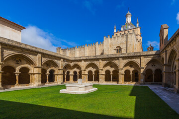 A sunlit courtyard with a central stone fountain is surrounded by arched cloisters