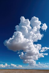 Massive cumulus clouds billow across a bright blue sky over a vast desert landscape during the afternoon