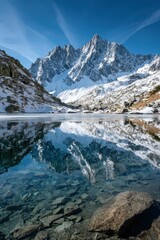 Snow-capped mountains reflect in a calm alpine lake on a clear day in the great outdoors
