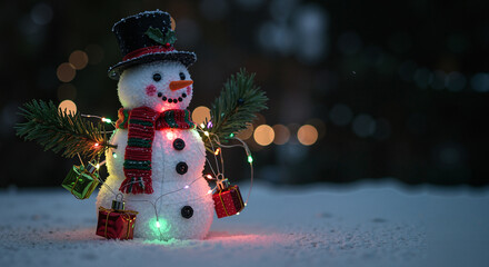 Obraz premium Christmas snowman decorated with lights and gifts in snowy landscape 