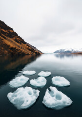 Floating icebergs in jokulsarlon glacier lagoon in iceland with mountains and cloudy sky