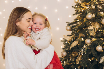 Mother embracing daughter near decorated christmas tree
