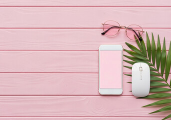 Top view of smartphone with sunglasses, computer mouse and palm leaf on pink wooden background