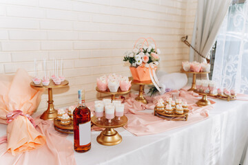Elegant dessert table with cupcakes, sweets, and wine in a romantic pink and gold setting for a festive celebration