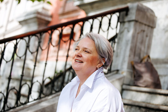Smiling elderly caucasian female in white shirt on outdoor stairs