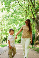 Obraz premium Caucasian mother and son enjoy leisure time in park walking and talking, smiling laughing. Serene family connection.